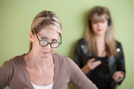 Article header image of a suspicious mom with a teenager in the background on her phone
